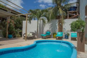a pool with blue chairs and a palm tree at Pousada Jerimar in Jericoacoara +29 photos