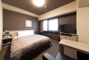 Hotel Route-Inn Osaka Kishiwada -Higashikishiwada Ekimae Kansai Airport- في Kishiwada: غرفة نوم بسرير وتلفزيون بشاشة مسطحة