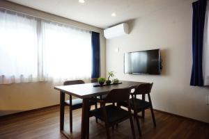 a dining room with a table and chairs and a television at RoNa Hotel in Tokyo