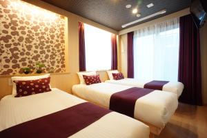 a hotel room with three beds and a window at RoNa Hotel in Tokyo