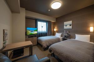 Hotel Route-Inn Ichihara في Ichihara: غرفة فندقية بسريرين وتلفزيون بشاشة مسطحة