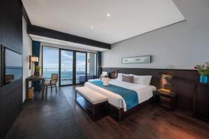 a bedroom with a large bed with a view of the ocean at Howard Johnson Sandalwoods Resort Huizhou in Huidong