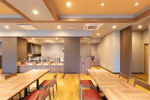 un ristorante con tavoli e sedie in legno e bancone di Hotel Route-Inn Sakurai Ekimae a Sakurai