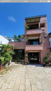 a pink building with a balcony and some plants at A&L Inn 戀灣旅棧 in Nanwan