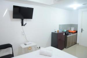 a room with a tv on the wall and a kitchen at Comfy Studio Poris 88 Apartment By Travelio in Poris-lor