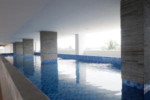 a swimming pool with blue tiles and pillars in a building at Comfy Studio Poris 88 Apartment By Travelio in Poris-lor