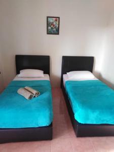 dwa łóżka siedzące obok siebie w pokoju w obiekcie Tokman Inn w mieście Pantai Cenang