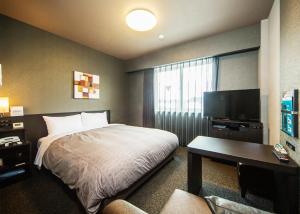 a hotel room with a bed and a flat screen tv at Hotel Route-Inn Katori Sawara Ekimae in Katori