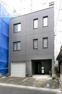 a gray brick building with a garage at Uhome Otsuka Villa in Tokyo