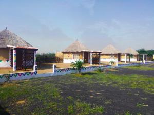 una fila di capanne con tetti di paglia in un campo di Banni Village Stay a Bherandiāla