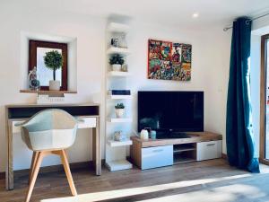 a living room with a tv and a desk and a chair at L'étape du moulin in Barbaste