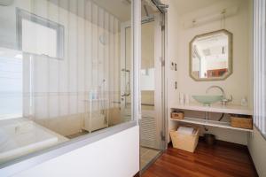 une salle de bain avec une baignoire, un lavabo et un miroir dans l'établissement ホテル 美らビーチ, à Motobu 78 autres photos