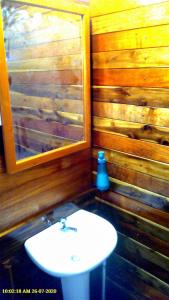 uma casa de banho com um lavatório branco e um espelho. em Hummingbird Rest a fully equipped cabana in subtropic garden em San Ignacio