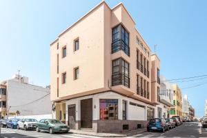 budynek na rogu ulicy z zaparkowanymi samochodami w obiekcie Apartamento Pizarro 1b w Corralejo