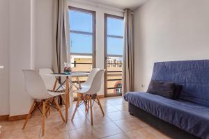 sala de estar con sofá azul, mesa y sillas en Apartamento Pizarro 2b, en Corralejo