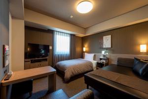 a hotel room with a bed and a couch at Hotel Route-Inn Kanuma Inter in Kanuma