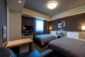 a hotel room with two beds and a couch at Hotel Route-Inn Kanuma Inter in Kanuma