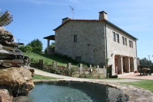 a stone house with a pond in front of it at Casa Da Oliveirinha in Casco
