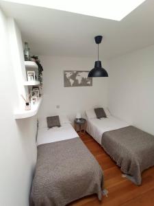 two beds in a room with white walls at La casa de LA FLORA a 3 minutos de la catedral VUT09187 in Burgos