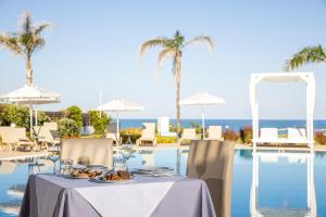 a table with a plate of food next to a swimming pool at Sentido Asterias Beach Resort in Afantou