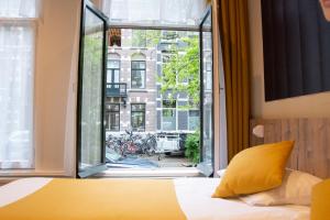 a bedroom with a bed and a large window at Hotel Asterisk, a family run hotel in Amsterdam