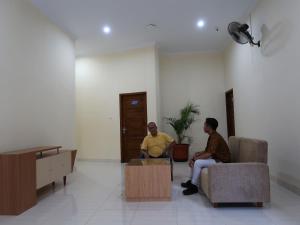 two men sitting on chairs in a room at Solota Kostel Syariah in Bonorejo
