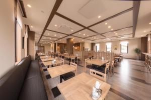 an empty restaurant with wooden tables and chairs at Hotel Route-Inn Kurashiki Mizushima in Kurashiki