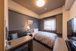 a hotel room with a bed and a flat screen tv at Hotel Route-Inn Kurashiki Mizushima in Kurashiki
