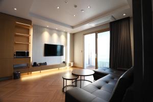 a living room with a couch and a tv at Sunrise Hotel Sokcho in Sokcho