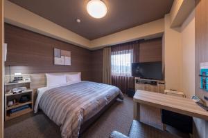 ein Hotelzimmer mit einem Bett und einem Flachbild-TV in der Unterkunft Hotel Route-Inn Kurashiki Mizushima in Kurashiki