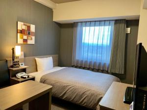 Habitación de hotel con cama y ventana en Hotel Route-Inn Takefu Inter en Echizen