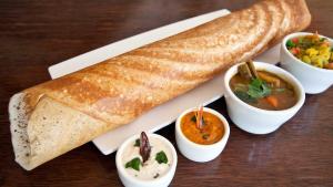 a plate of food with a loaf of bread and some dips at Lloyds Serviced Apartments,Krishna Street,T Nagar in Chennai