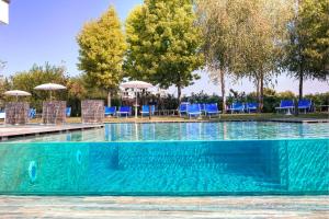 una gran piscina con sillas azules y árboles en Hotel Terme Belsoggiorno, en Abano Terme