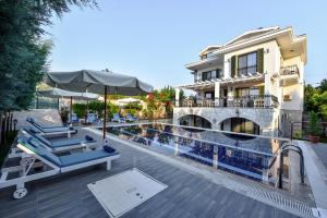 a pool with lounge chairs and an umbrella next to a building at Villa TN - Fethiye in Fethiye