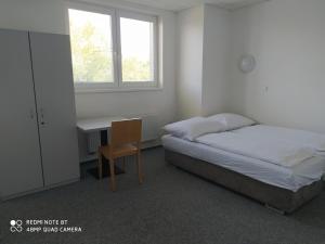 um quarto com uma cama, uma secretária e uma janela em Penzion ValMez em Valašské Meziříčí