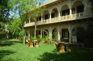 a yard with tables and chairs in front of a building at The Birder's Inn in Bharatpur