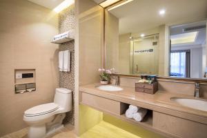 a bathroom with a toilet and two sinks and a mirror at Wyndham Hainan Clearwater Bay Resort in Lingshui