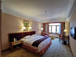 a hotel room with a bed and a television at Qingdao Oceanwide Elite Hotel in Qingdao