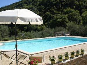 a swimming pool with an umbrella and a chair at Belvilla by OYO Villa Monte Acuto in Galera