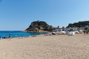 a beach with people and boats in the water at Desconnectar Tossa de Mar in Tossa de Mar