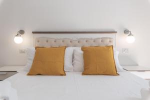 um quarto com uma cama branca e almofadas amarelas em Vicolo del Cinque Apartment Trastevere em Roma