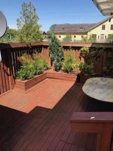 a deck with potted plants and a table at Lägenhet med 2 sovrum och uteplats in Oxie