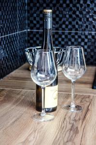 zwei Weingläser und eine Flasche auf einem Holztisch in der Unterkunft Fürge cselle apartman in Tapolca