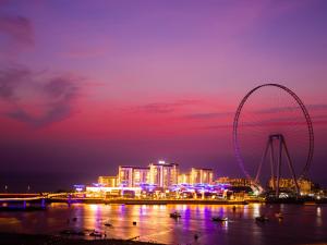 Roda Amwaj Suites Jumeirah Beach Residence في دبي: أفق المدينة مع عجل فيريس في الليل