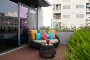 un sofá al aire libre con almohadas coloridas en el balcón en HOME Hotel en Ho Chi Minh