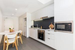 een witte keuken met een tafel en een magnetron bij KOZYGURU FORTITUDE VALLEY AMAZING VIEW 2BED APT + FREE PARKING QFV010 in Brisbane