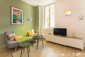 uma sala de estar com um sofá verde e uma televisão em Mini maison studio Ancienne Rénovée +Parking em Avignon