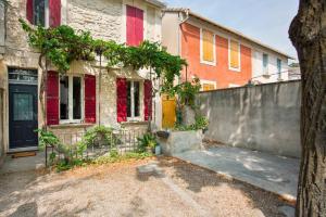 an old house with red windows and a fence at Mini maison studio Ancienne Rénovée +Parking in Avignon