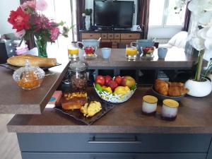 einen Frühstückstisch mit Obst und anderen Lebensmitteln auf der Theke in der Unterkunft LES BIGORNEAUX in Saint-Suliac