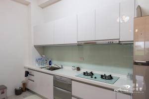 una cocina con armarios blancos y fregadero en Shan Hao Homestay en Yilan City